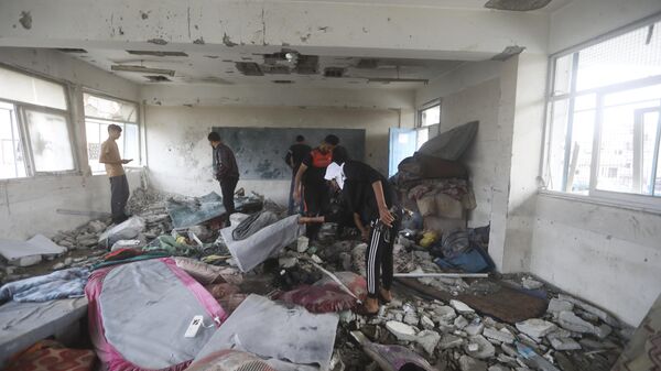 Палестинцы на месте израильского удара по школе Ближневосточного агентства ООН в секторе Газа