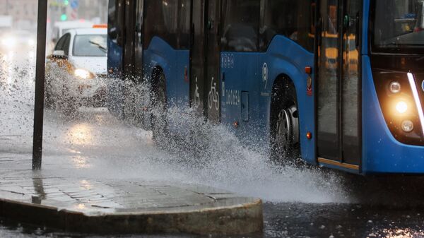 Автобус движется по проезжей части дороги во время дождя в центре Москвы