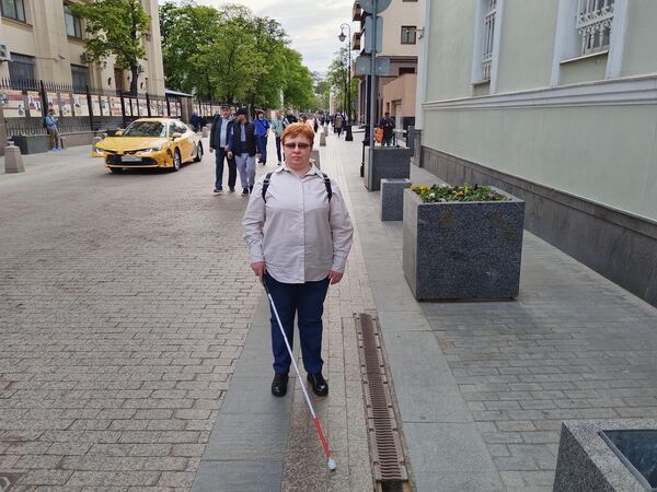 Мария Финогенова стоит на улице, где нет границы между тротуаром и проезжей частью