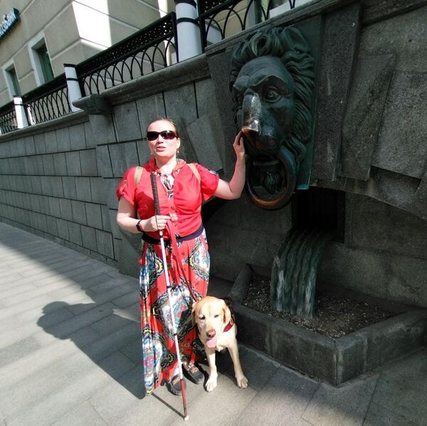 Светлана Телицына стоит возле барельефа в виде головы льва, расположенном на доме номер 3 в Гагаринском переулке Москвы