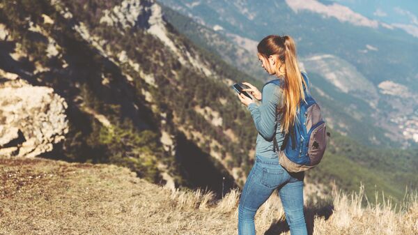 Девушка использует смартфон в горах