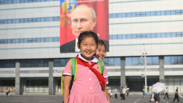 Школьницы недалеко от здания, на котором вывешен баннер с портретом президента РФ Владимира Путина, в Пхеньяне