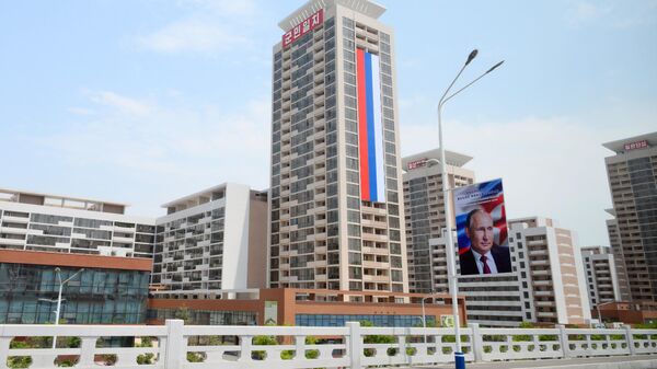 Российский флаг на здании и баннер с портретом президента РФ Владимира Путина на улице в Пхеньяне