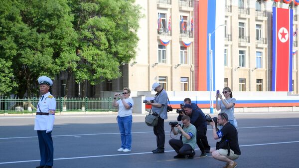 Журналисты занимаются фотосъемкой на улице в Пхеньяне перед визитом президента России Владимира Путина