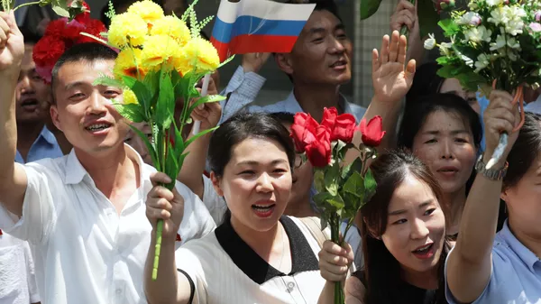 Люди приветствуют кортеж президента РФ Владимира Путина на улице в Пхеньяне Люди приветствуют кортеж президента РФ Владимира Путина на улице в Пхеньяне