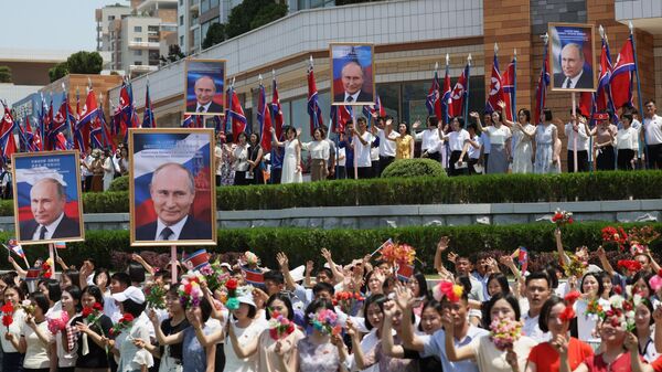 Люди приветствуют кортеж президента РФ Владимира Путина на улице в Пхеньяне
