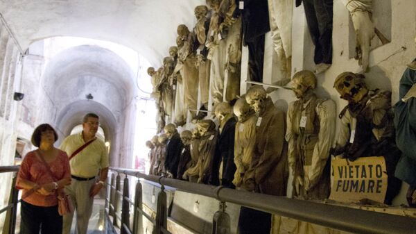 Туристы проходят мимо мумифицированных трупов, хранящихся в катакомбах капуцинов, Палермо, Сицилия
