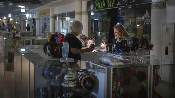 Продавец показывает товары покупателю при помощи фонарика в подземном торговом центре во время отключения электроэнергии в Киеве