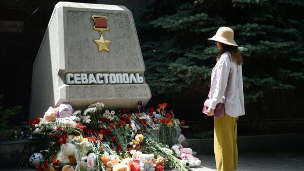 Женщина возле стихийного мемориала  у стелы Севастополя на Аллее городов-героев в день траура по погибшим в результате ракетной атаки ВСУ