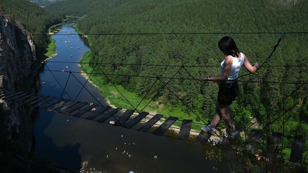 Девушка идет по подвесному мосту в экстрим парке Grifon в Челябинской области