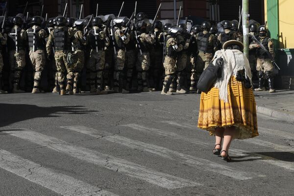 Женщина проходит мимо военной полиции на площади Мурильо в Ла-Пасе, Боливия