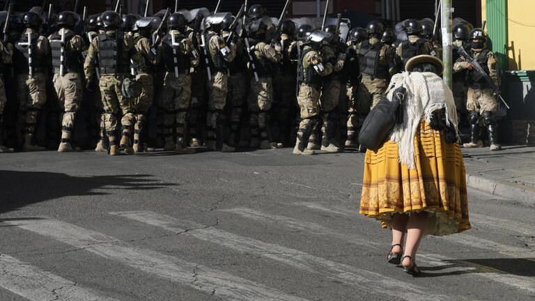 Женщина проходит мимо военной полиции на площади Мурильо в Ла-Пасе, Боливия