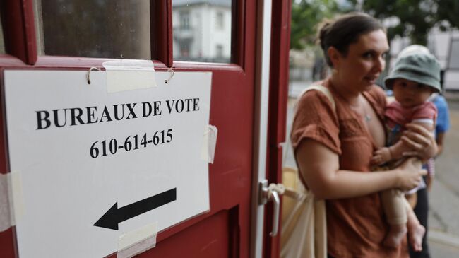 Женщина с ребенком возле избирательного участка в Страсбурге во время первого тура выборов в Национальное собрание Франции