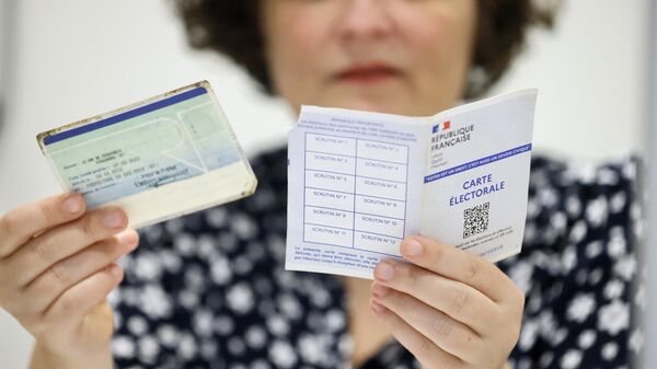 Ассистент проверяет документы избирателя на парламентских выборах во Франции