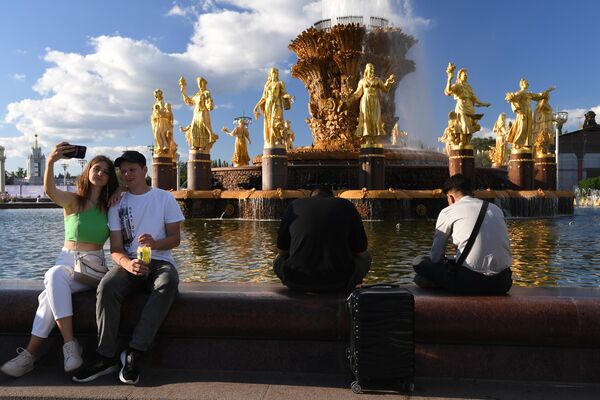 Люди отдыхают у фонтана Дружба народов на ВДНХ в Москве