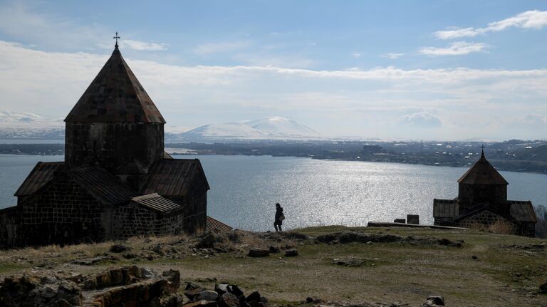 Турист на территории монастыря Севанаванк на побережье озера Севан в Армении