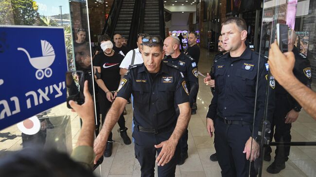Израильская полиция арестовывает мужчину после теракта с ножом в торговом центре в городе Кармиэль на севере Израиля. 3 июля 2024