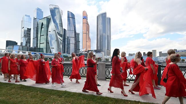 Девушки и женщины участвуют в акции Проекта в красных платьях на набережной Тараса Шевченко в Москве