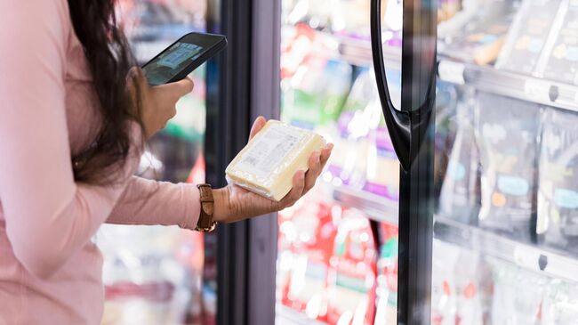 Девушка сканирует штрих-код упаковки сыра в супермаркете