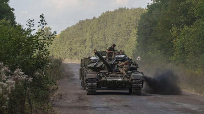 Украинские военнослужащие едут на танке с табличкой Любимовка недалеко от российско-украинской границы в Сумской области