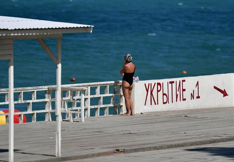 Женщина неподалеку от модульного укрытия для защиты людей при обстрелах на набережной в Учкуевке. Укрытие представляет собой железобетонную конструкцию с двойным армированием