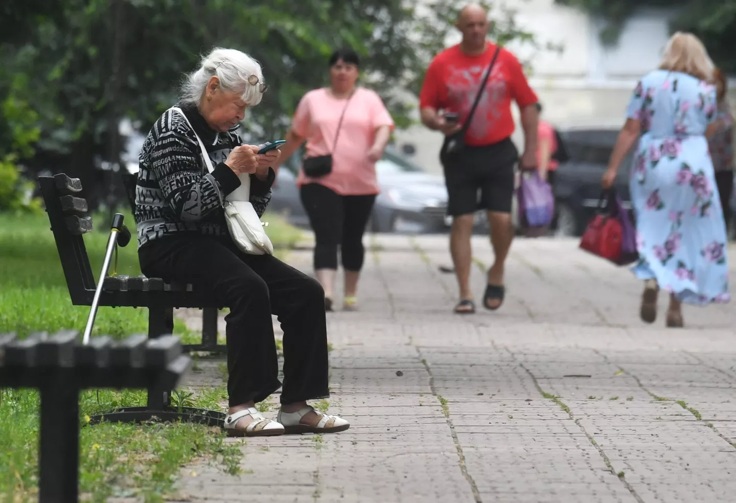 Пожилая женщина на скамейке в сквере