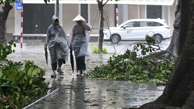 Жители Ханоя на улице города во время тайфуна Яги