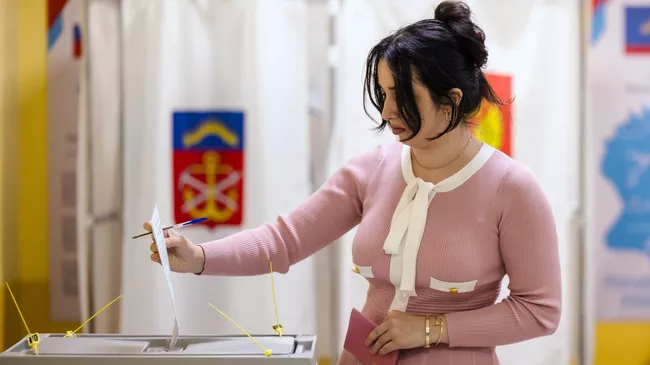 Женщина голосует на выборах губернатора Мурманской области и депутатов в горсоветы на избирательном участке в Мурманске