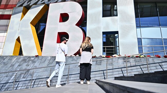Люди возлагают цветы у молодежного центра Планета КВН в память о ведущем Александре Маслякове