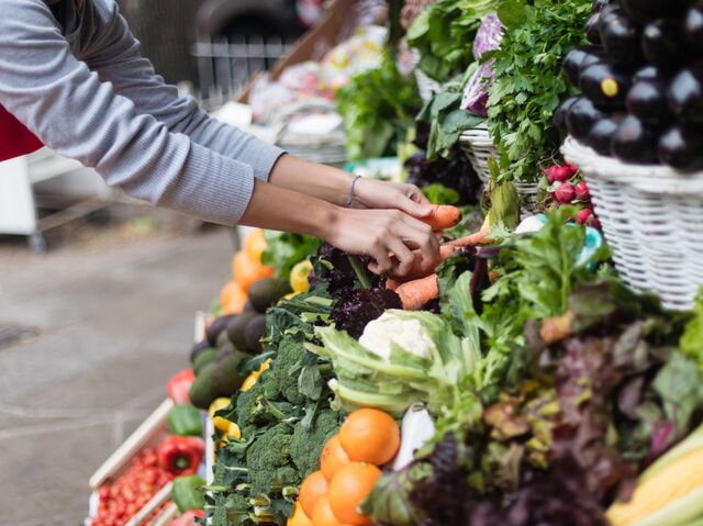 Женщина-продавец раскладывает овощи на прилавке