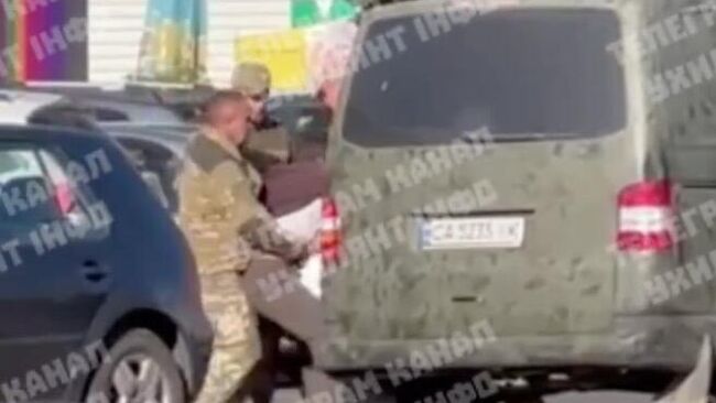 Сотрудники ТЦК заталкивают мужчину в автобус в городе Черкассы, Украина. Кадр видео