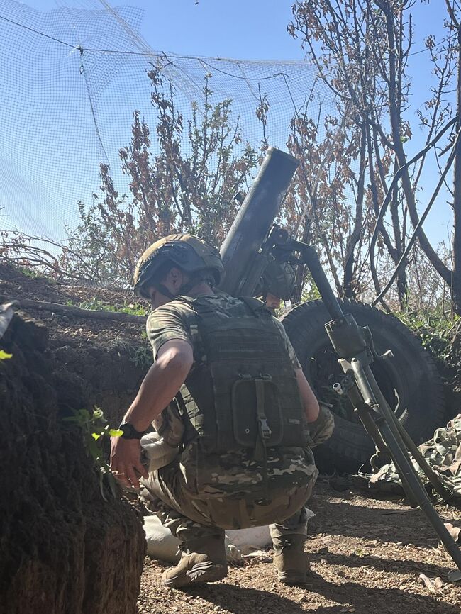 Боец заряжает миномет