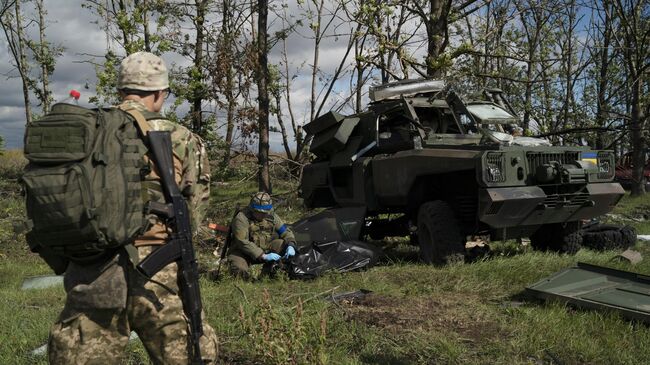 Украинские военнослужащие рядом с уничтоженным бронетранспортером ВСУ в Харьковской области