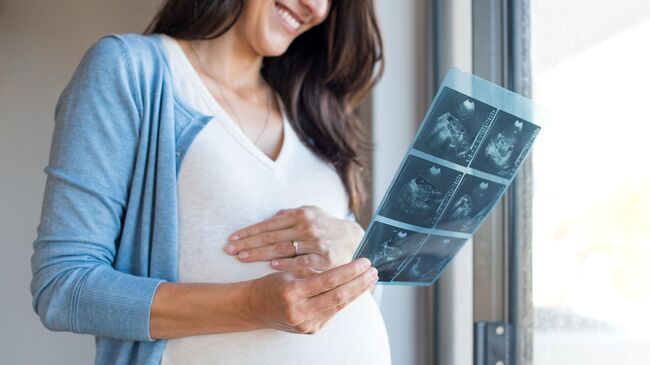 Беременная женщина смотрит на снимок после УЗИ 