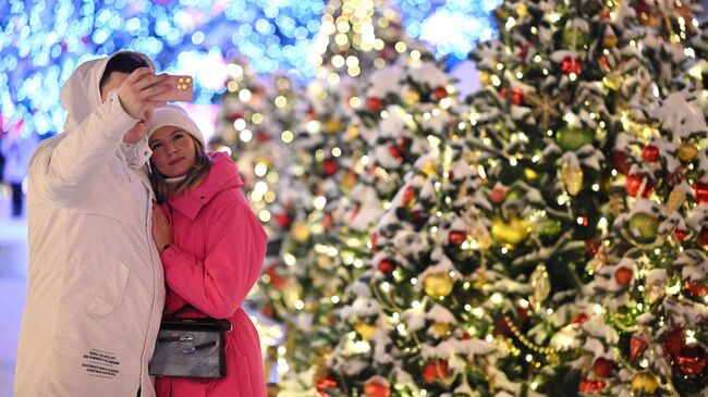 Люди фотографируются на фоне новогодних украшений у Парка Горького в Москве
