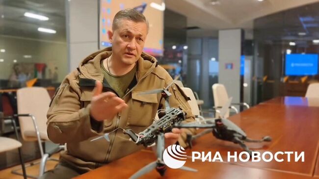 Военно-политический эксперт Ян Гагин демонстрирует аналог беспилотника, которым он был атакован под Донецком летом 2024 года. Кадр видео