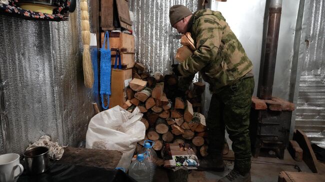 Боец добровольческого отряда занимается заготовкой дров Боец добровольческого отряда занимается заготовкой дров