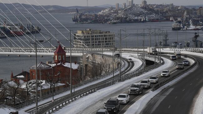 Автомобили едут по Золотому мосту во Владивостоке после сильного снегопада