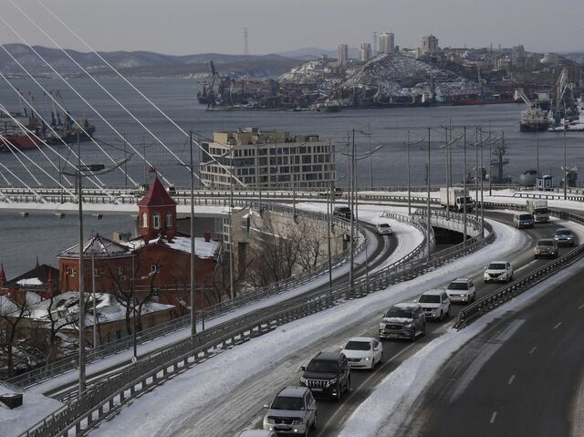 Автомобили едут по Золотому мосту во Владивостоке после сильного снегопада