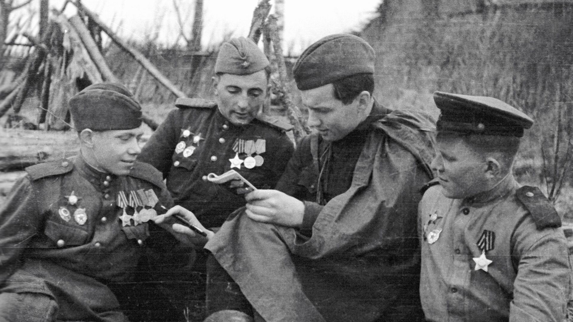 Советский журналист, военный корреспондент Константин Лапин (второй справа) беседует с бойцами фронта в освобожденной деревне Каруза Калининской области   - РИА Новости, 1920, 28.02.2025