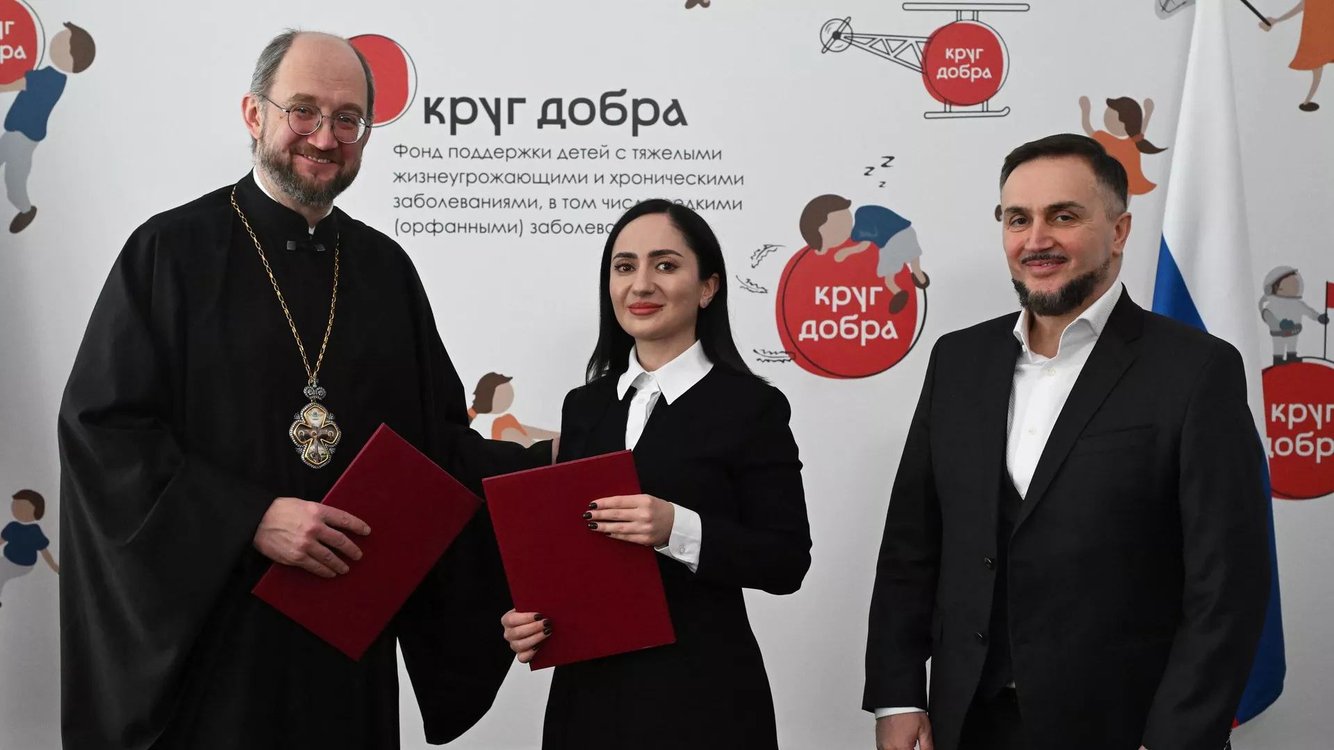 Председатель правления Фонда Круг добра, председатель Комиссии по вопросам социального партнерства, попечения и развитию инклюзивных практик Общественной Палаты РФ протоиерей Александр Ткаченко, директор культурно-благотворительного фонда Ашана Мактина Джинджолия и учредитель фонда Ашана Беслан Шакая на церемонии подписания соглашения о сотрудничестве в Москве - РИА Новости, 1920, 26.02.2025