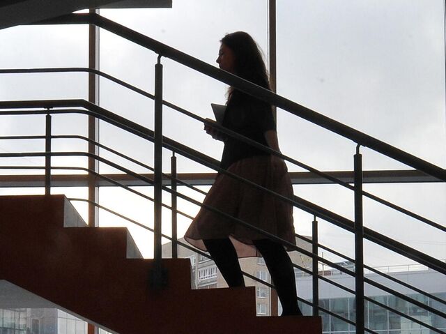 Девушка поднимается по лестнице в офисе 