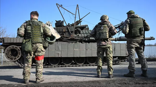 Военнослужащие группировки войск Север ВС РФ возле подбитого танка М1 Абрамс ВСУ,  эвакуированного из-под Суджи в ходе специальной военной операции