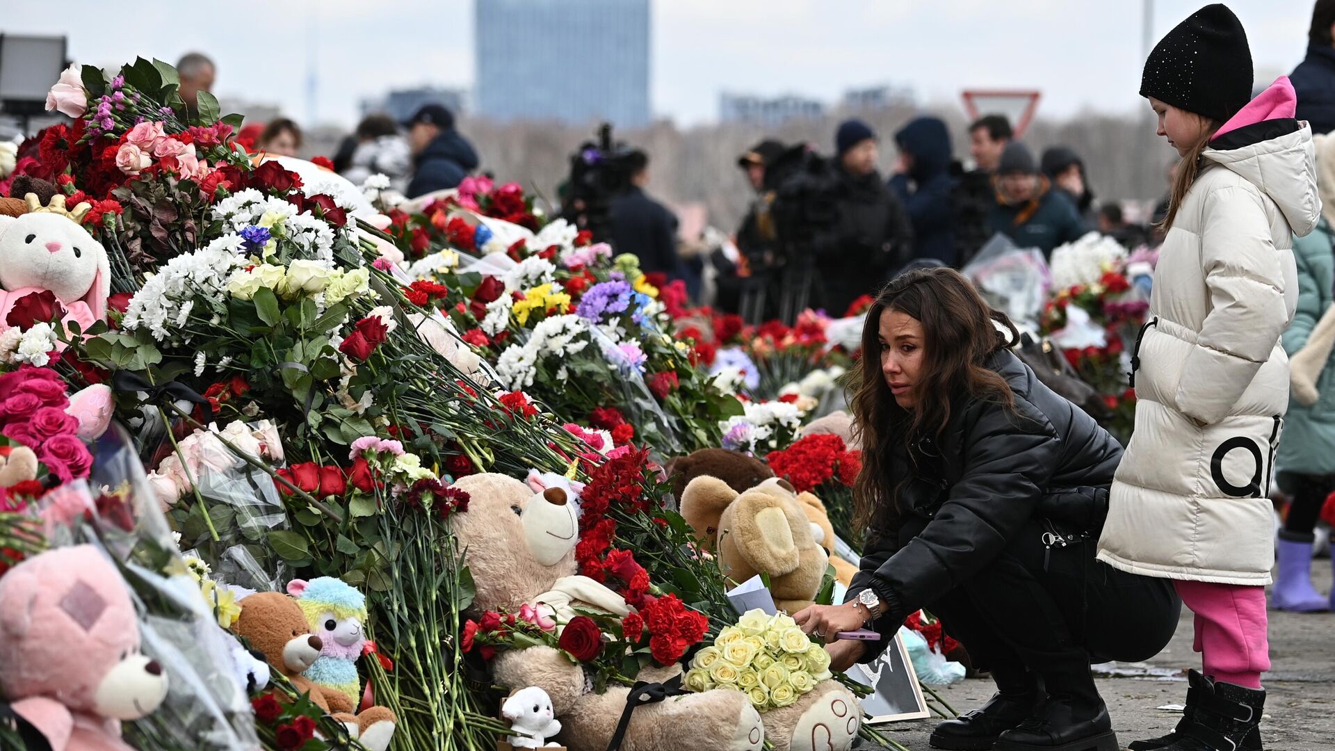 Девушка возлагает цветы у стихийного мемориала у здания концертного зала Крокус Сити Холл, где произошла стрельба и начался пожар - РИА Новости, 1920, 21.03.2025