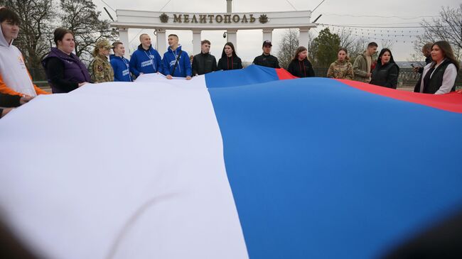 Активисты молодежного движения Юг молодой совместно с другими организациями развернули флаг РФ на площади Победы в Мелитополе в рамках празднования годовщины воссоединения Крыма с Россией