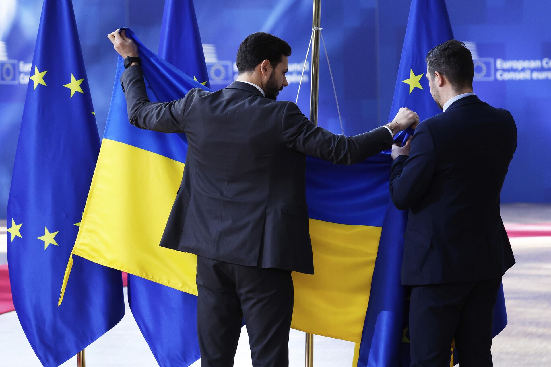 Сотрудники службы протокола вывешивают флаг Украины перед приездом Владимира Зеленского в Брюссель - РИА Новости, 1920, 08.07.2025
