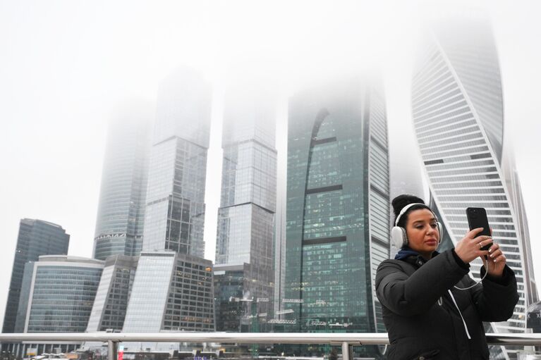 Девушка фотографируется на фоне небоскребов международного делового центра Москва-сити Девушка фотографируется на фоне небоскребов международного делового центра Москва-сити