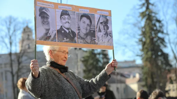 Жительница Литвы держит фотографии погибших американских военных на акции памяти в Вильнюсе