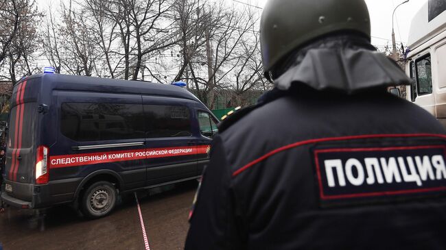 Сотрудник полиции рядом с автомобилем Следственного комитета России