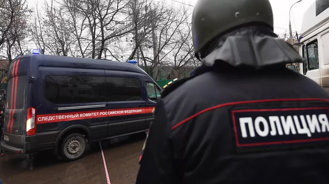 Сотрудник полиции рядом с автомобилем Следственного комитета России